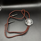 Mexico Silver 25 Pesos Hand Cut Coin Bolo Tie with darker brown leather cord on black background.
