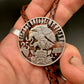 Mexico Silver 25 Pesos Hand Cut Coin Bolo Tie with darker brown leather cord on a hand for display.