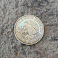 Mexico Silver 25 Pesos coin back on a grey rock surface.