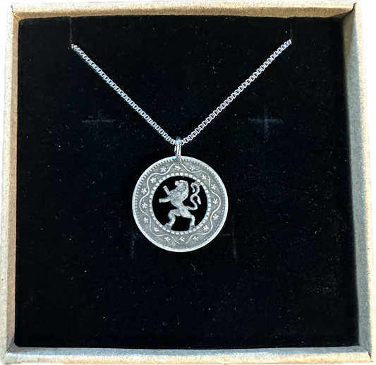 Belgium 10 Cents Lion hand cut coin necklace in a brown kraft box on a black velvet background.