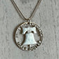 Cracked Liberty Bell U.S. Half Dollar Hand Cut Coin Necklace with snake chain on a white wood background.