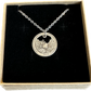 Idaho "River of No Return" Hand Cut Quarter Necklace with a stainless chain in a brown kraft box on a black velvet background.