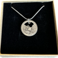 Idaho "River of No Return" Hand Cut Quarter Necklace with a snake chain in a brown kraft box on a black velvet background.