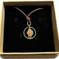 U.S. Indian Head Penny Coin Necklace with a leather cord in a brown kraft box on a black velvet background.