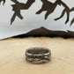 JFK Silver Half Dollar Coin Ring (front) on a light wood round with mountain outline in background.