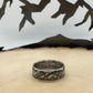 JFK Silver Half Dollar Coin Ring (front) on a light wood round with mountain outline in background.