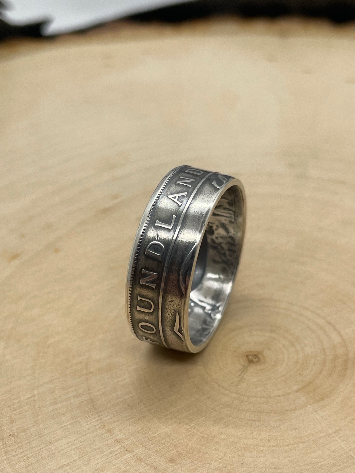 Newfoundland 50 Cents Silver Coin Ring on its edge on a light wood round.