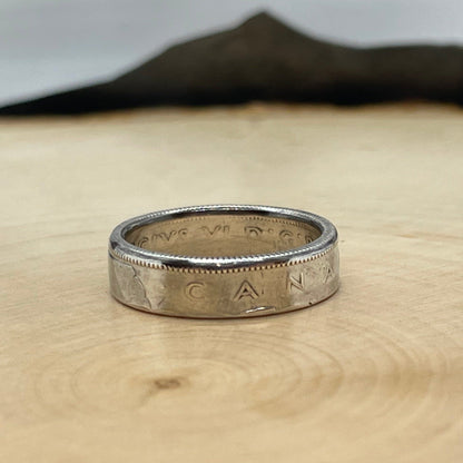 Canada 25 Cents Silver Coin Ring on a light wood round with a mountain outline background. - Mountainstruck Coin Jewelry