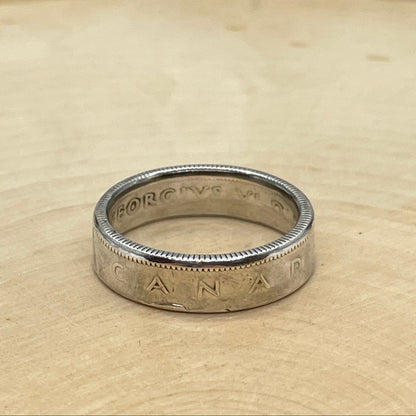 Canada 25 Cents Silver Coin Ring on a light wood round with a mountain outline background. - Mountainstruck Coin Jewelry