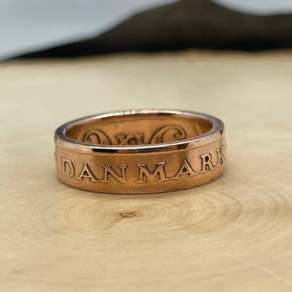 Denmark 5 Øre Coin Ring on a light wood round with a mountain outline background. - Mountainstruck Coin Jewelry