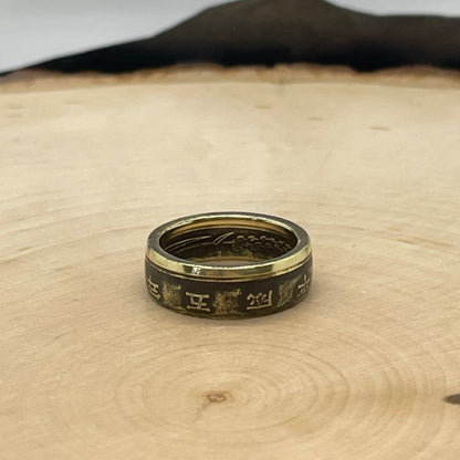 Japan 5 Yen Coin Ring on a light wood round with a mountain outline in the background. - Mountainstruck Coin Jewelry