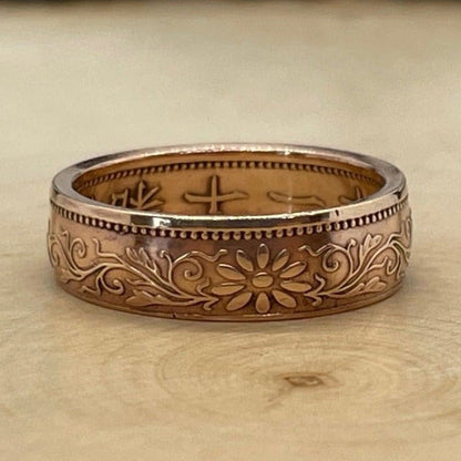 Japan One Sen Coin Ring on a light wood round with mountain outline in the background. - Mountainstruck Coin Jewelry