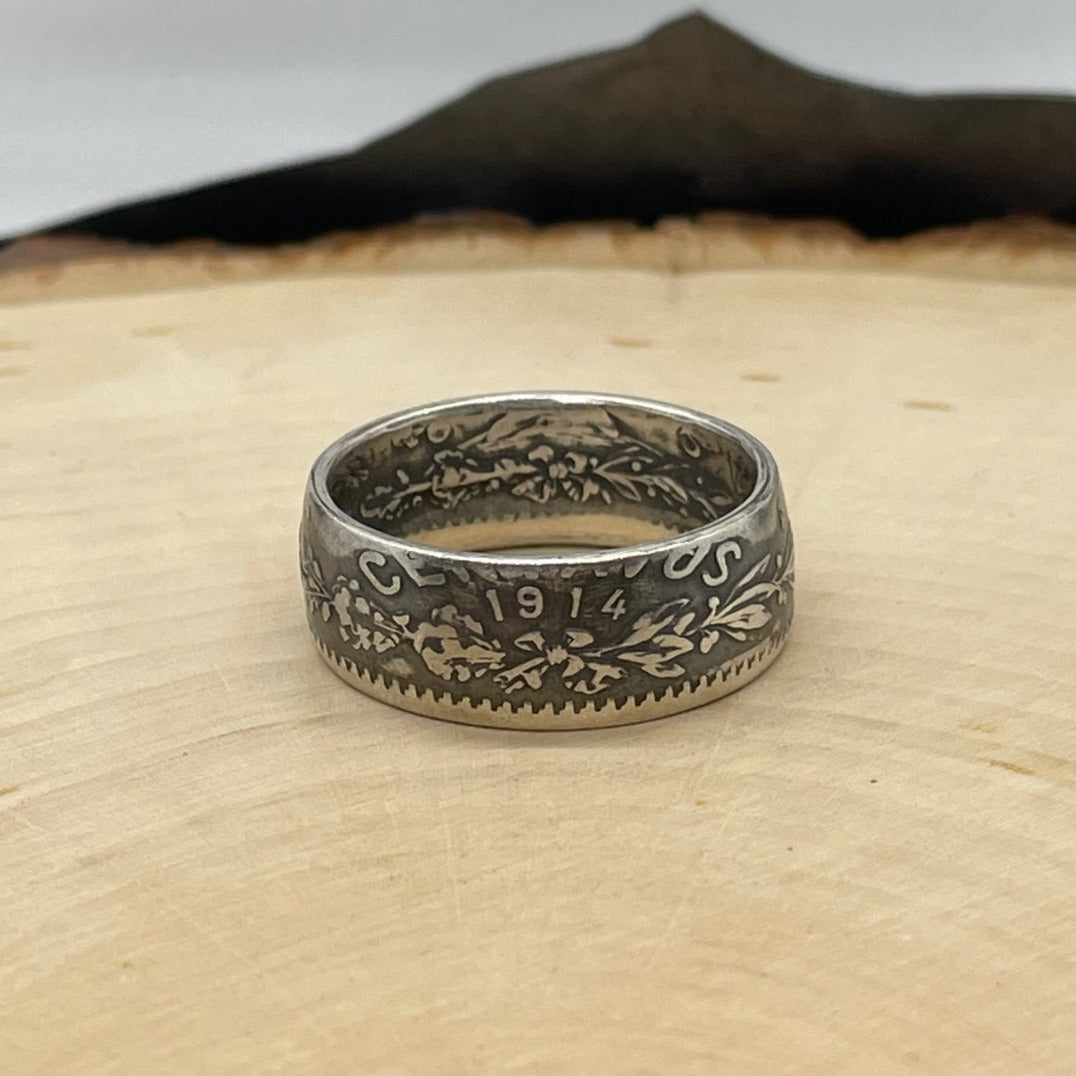 Mexico 50 Centavos Silver Coin Ring (Rare) on a light wood round with mountain outline in the background. - Mountainstruck Coin Jewelry