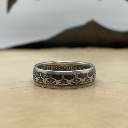 Newfoundland 20 Cents Silver Coin Ring on a light wood round with mountain outline in the background. - Mountainstruck Coin Jewelry