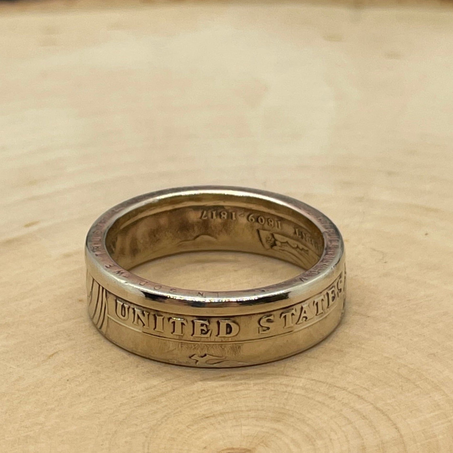 Presidential Gold Dollar Coin Ring on light wood round.