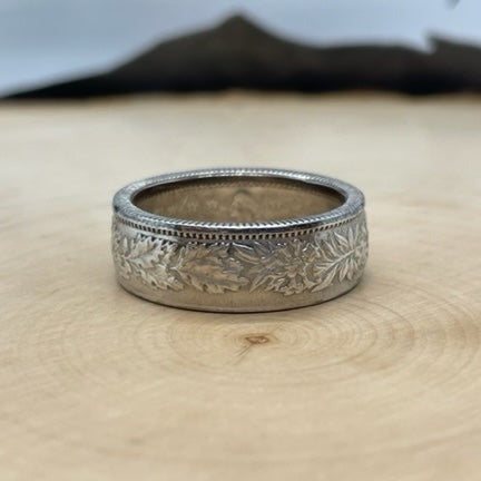 Swiss 2 Franc Silver Coin Ring (shine) on a light wood round with mountain outline in the background. - Mountainstruck Coin Jewelry