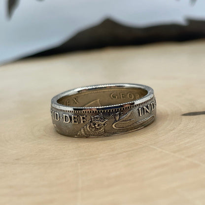 UK One Shilling Silver Coin Ring (shine) on a light wood round with a mountain outline in the background. - Mountainstruck Coin Jewelry