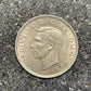 UK Two Shillings Silver Coin front on a concrete background.