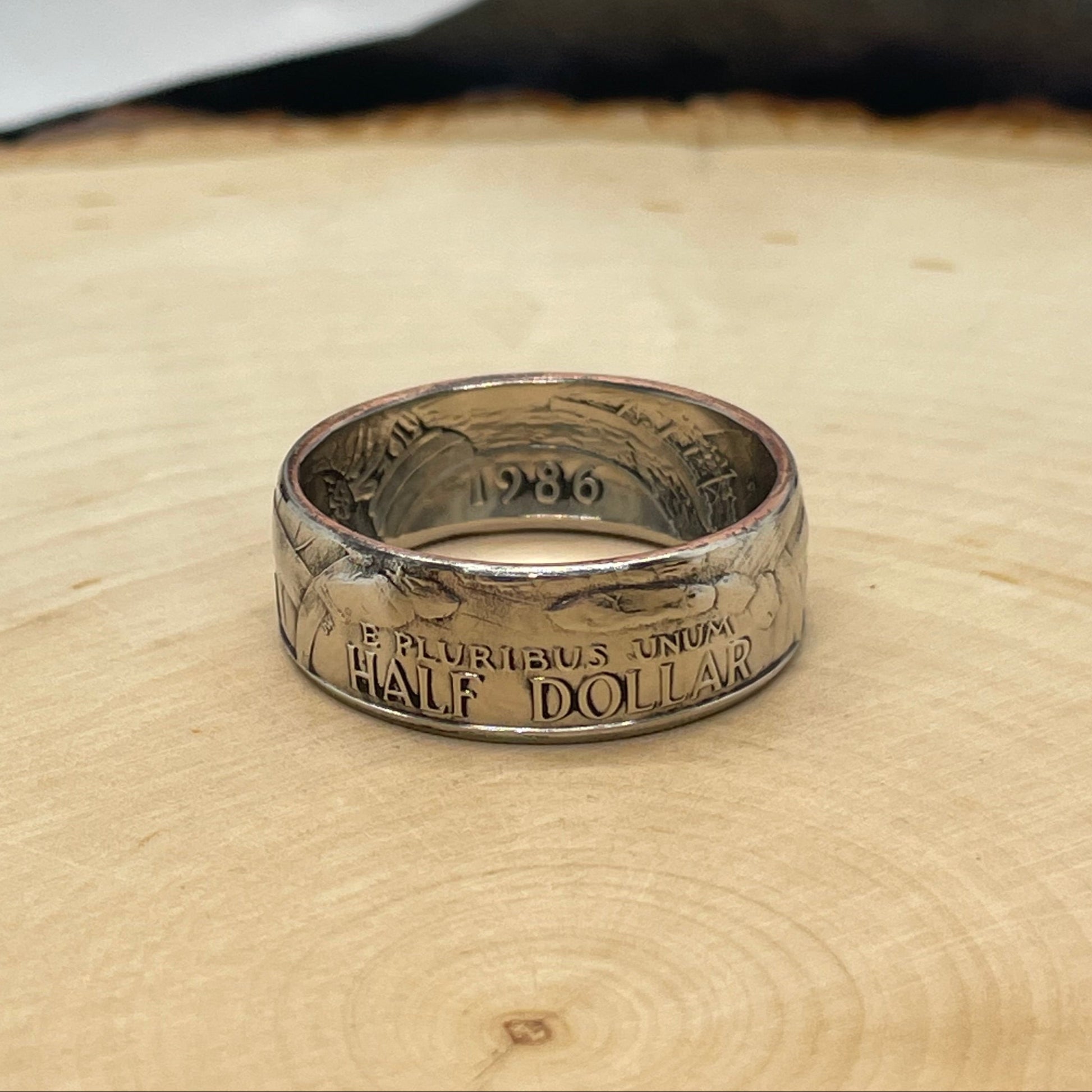 "A Nation of Immigrants" Half Dollar Coin Ring shined on a light wood round. - Mountainstruck Coin Jewelry