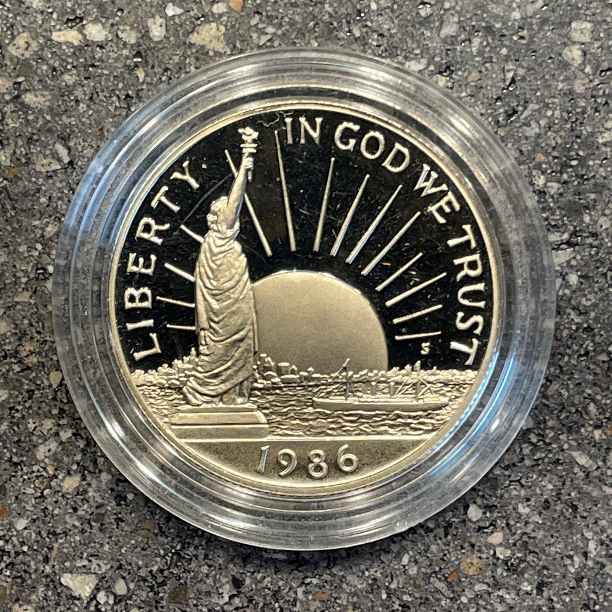 "A Nation of Immigrants" Half Dollar front of coin in a plastic case on a concrete background. - Mountainstruck Coin Jewelry