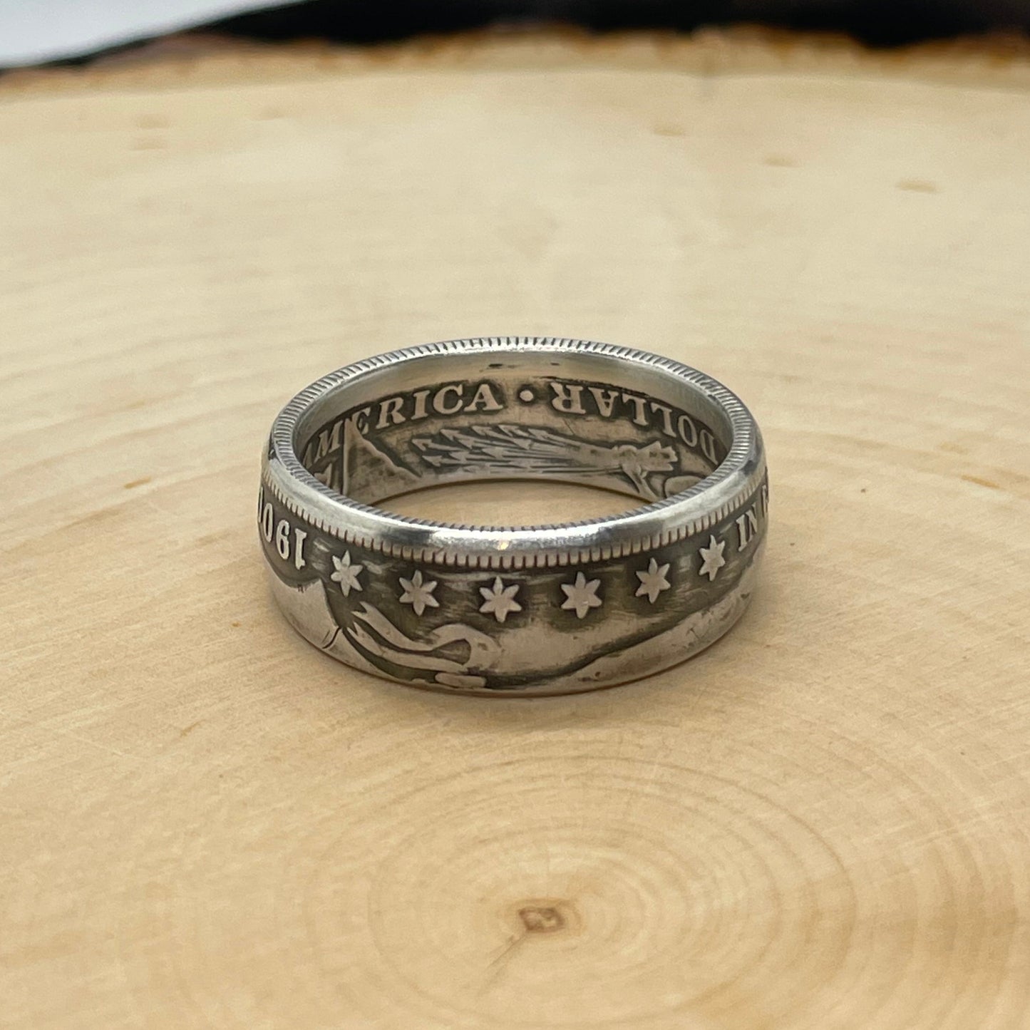 Barber Half Dollar Silver Coin Ring (front) on a light wood round with a mountain outline in the background. - Mountainstruck Coin Jewelry