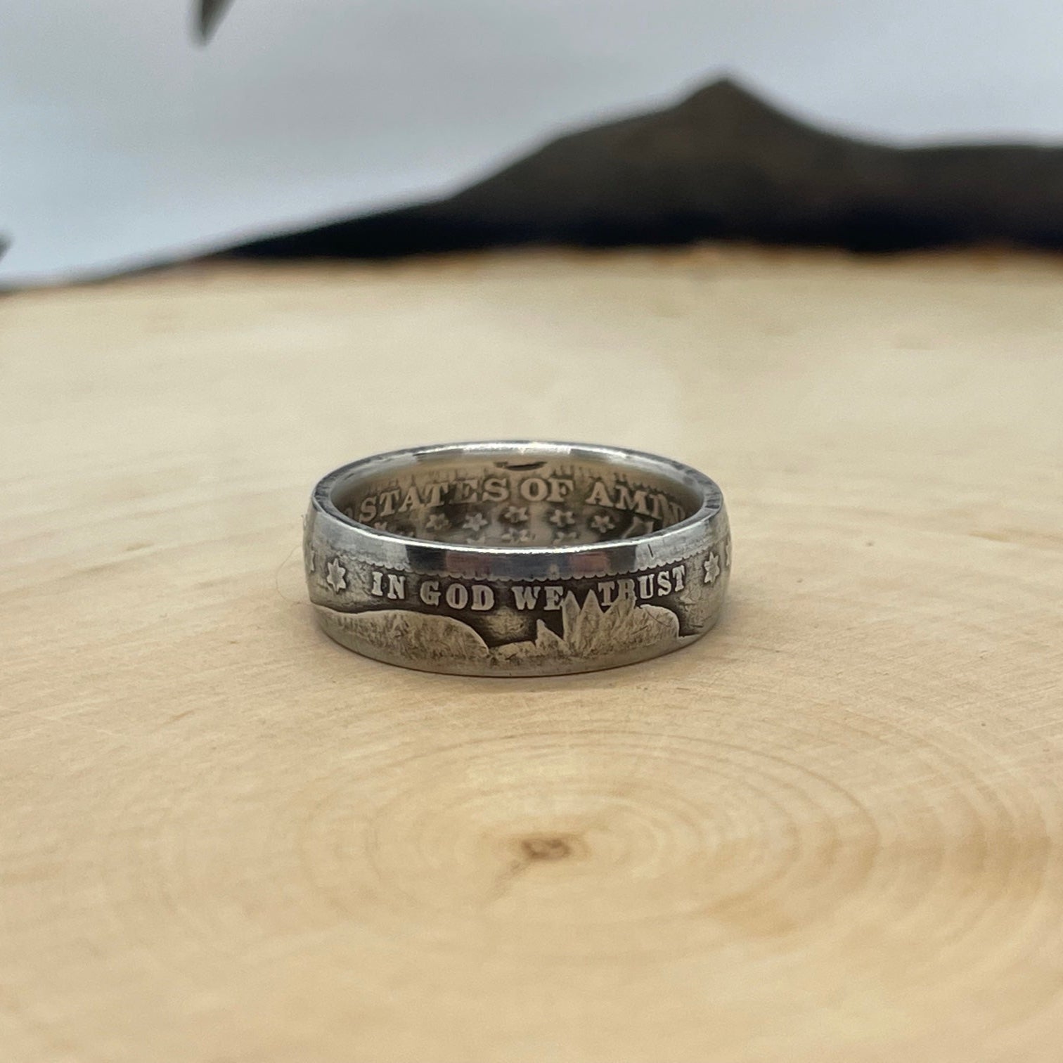 Barber Silver Quarter Coin Ring (front) on a light wood round with mountain outline in the background. - Mountainstruck Coin Jewelry