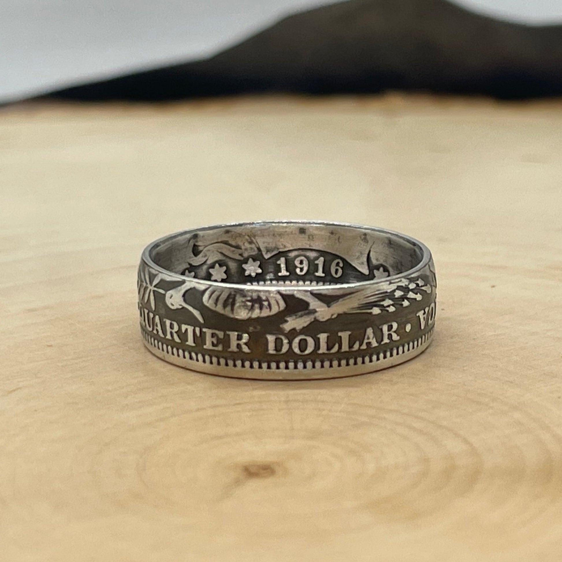 Barber Silver Quarter Coin Ring (reverse) on a wood round with mountain outline in the background. - Mountainstruck Coin Jewelry