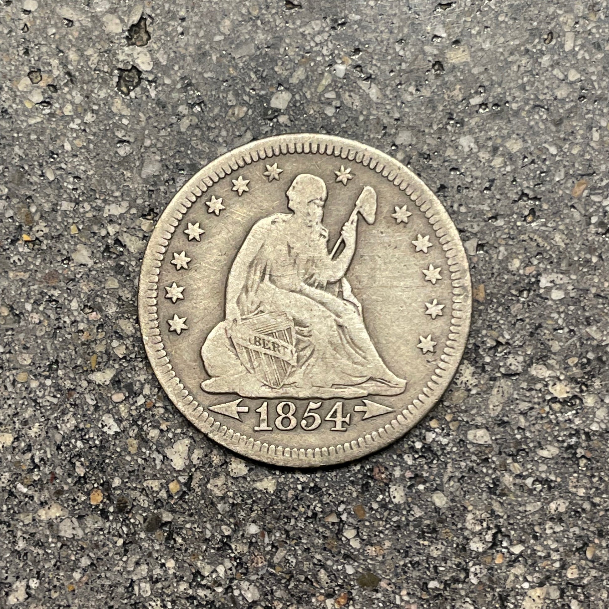 Seated Liberty Silver Quarter Coin front on a concrete background. - Mountainstruck Coin Jewelry