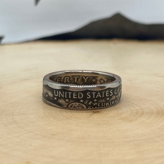 Susan B. Anthony Dollar Coin Ring on a light wood round with mountain outline in background. - Mountainstruck Coin Jewelry
