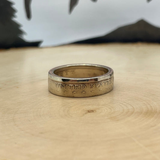 U.S. Sacagawea Dollar Coin Ring on a light wood round with mountain outline in background. - Mountainstruck Coin Jewelry