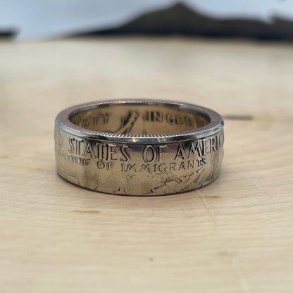 U.S. "A Nation of Immigrants" Half Dollar Coin Ring shined on light wood round. - Mountainstruck Coin Jewelry