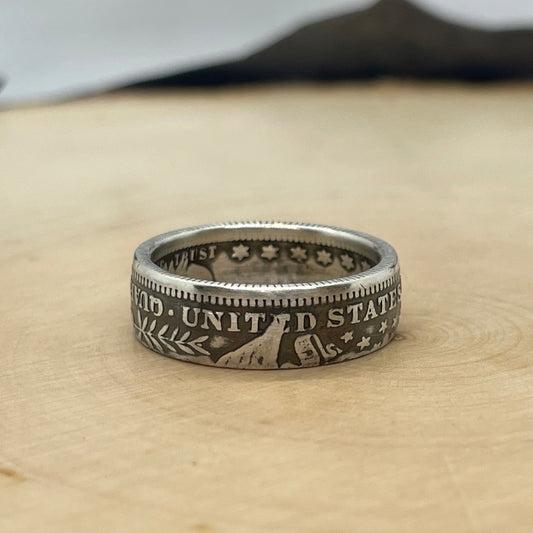U.S. Barber Silver Quarter Coin Ring (reverse) on a light wood round with metal mountain background. - Mountainstruck Coin Jewelry