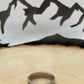 "V" Nickel Coin Ring on wood round with mountain outline in background.