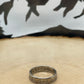 "V" Nickel Coin Ring on wood round with mountain outline in background.