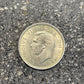 UK One Shilling Silver Coin front on a concrete background.