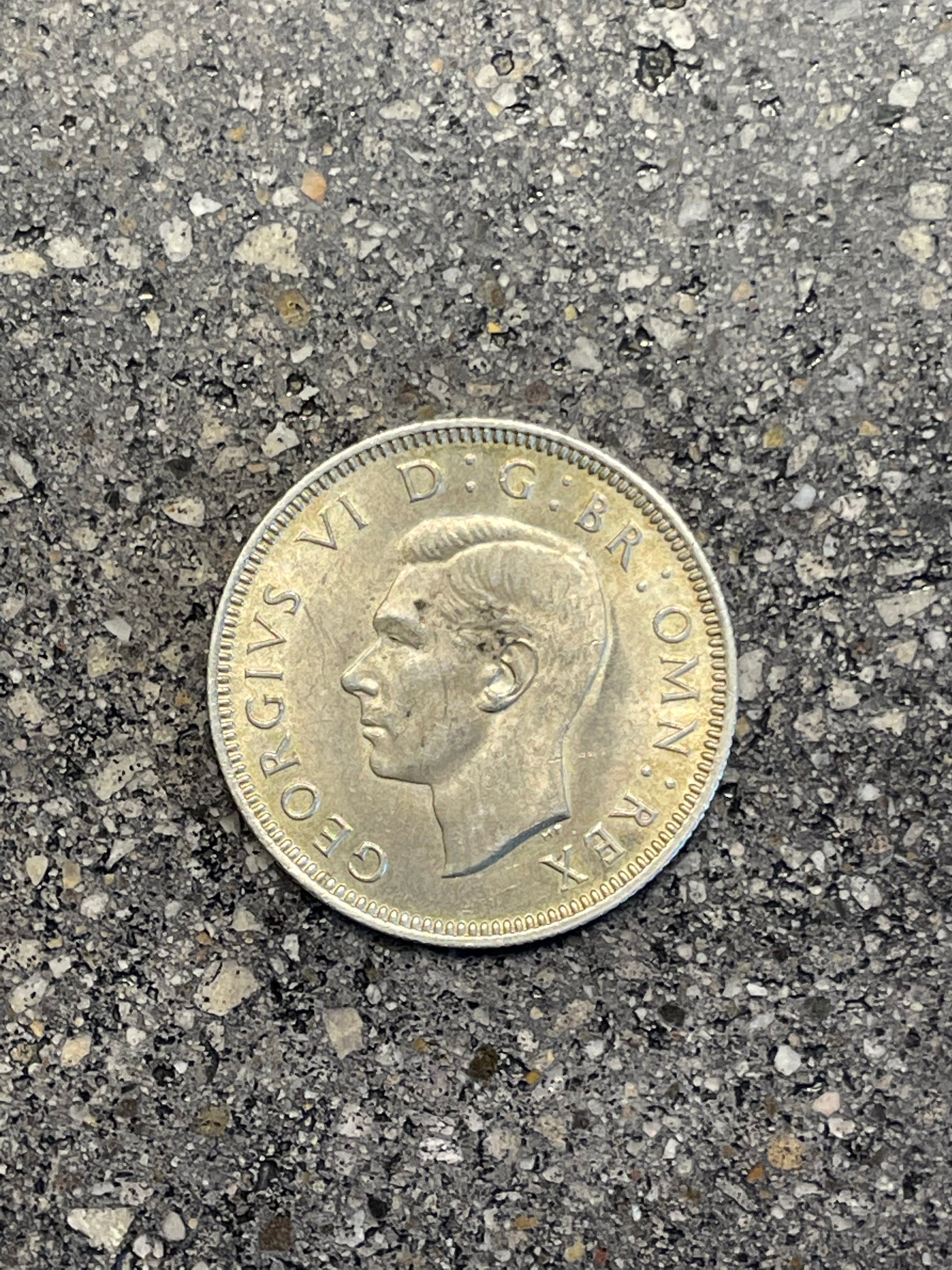 UK One Shilling Silver Coin front on a concrete background.