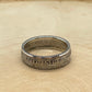 UK One Shilling Silver Coin Ring on a light wood round.