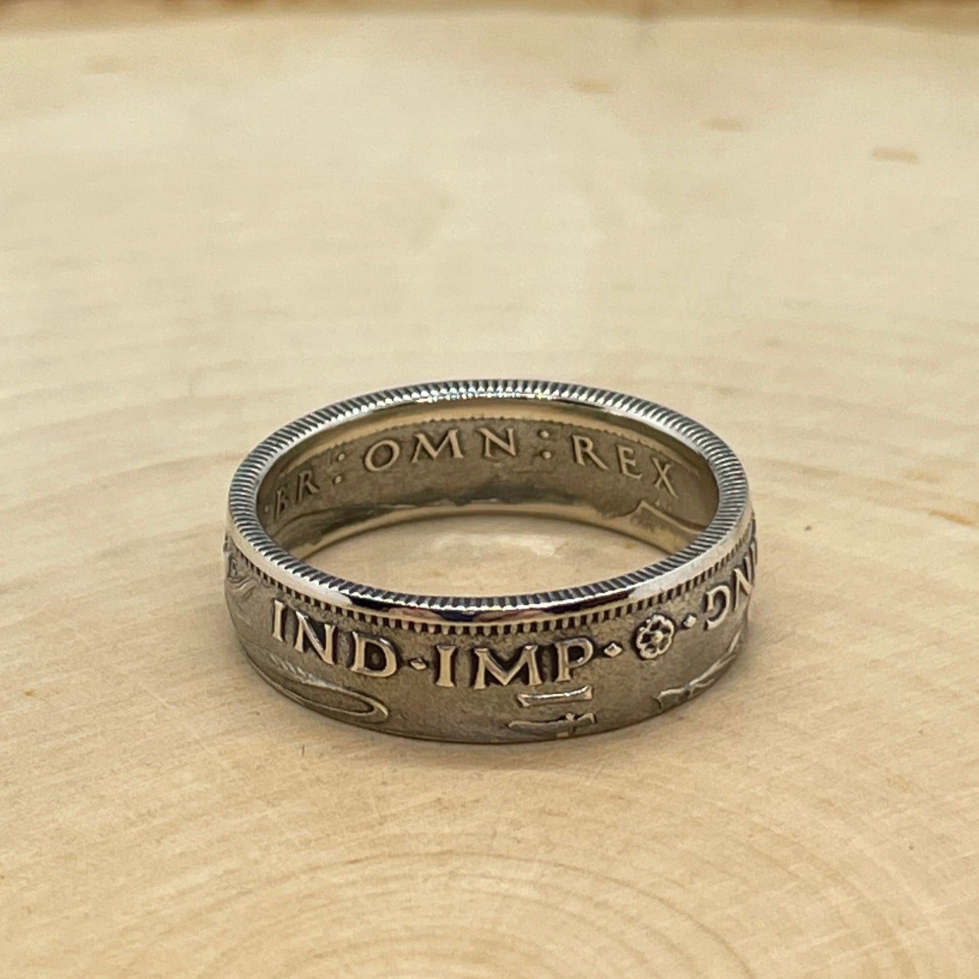 UK One Shilling Silver Coin Ring on a light wood round.