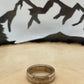 Sacagawea Dollar Coin Ring on a light wood round with mountain outline in background.