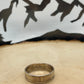 Sacagawea Dollar Coin Ring on a light wood round with mountain outline in background.