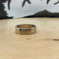 Sacagawea Dollar Coin Ring on a light wood round with mountain outline in background.