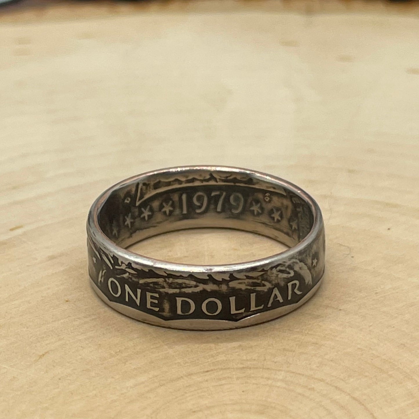 Susan B. Anthony Dollar Coin Ring on a light wood round.