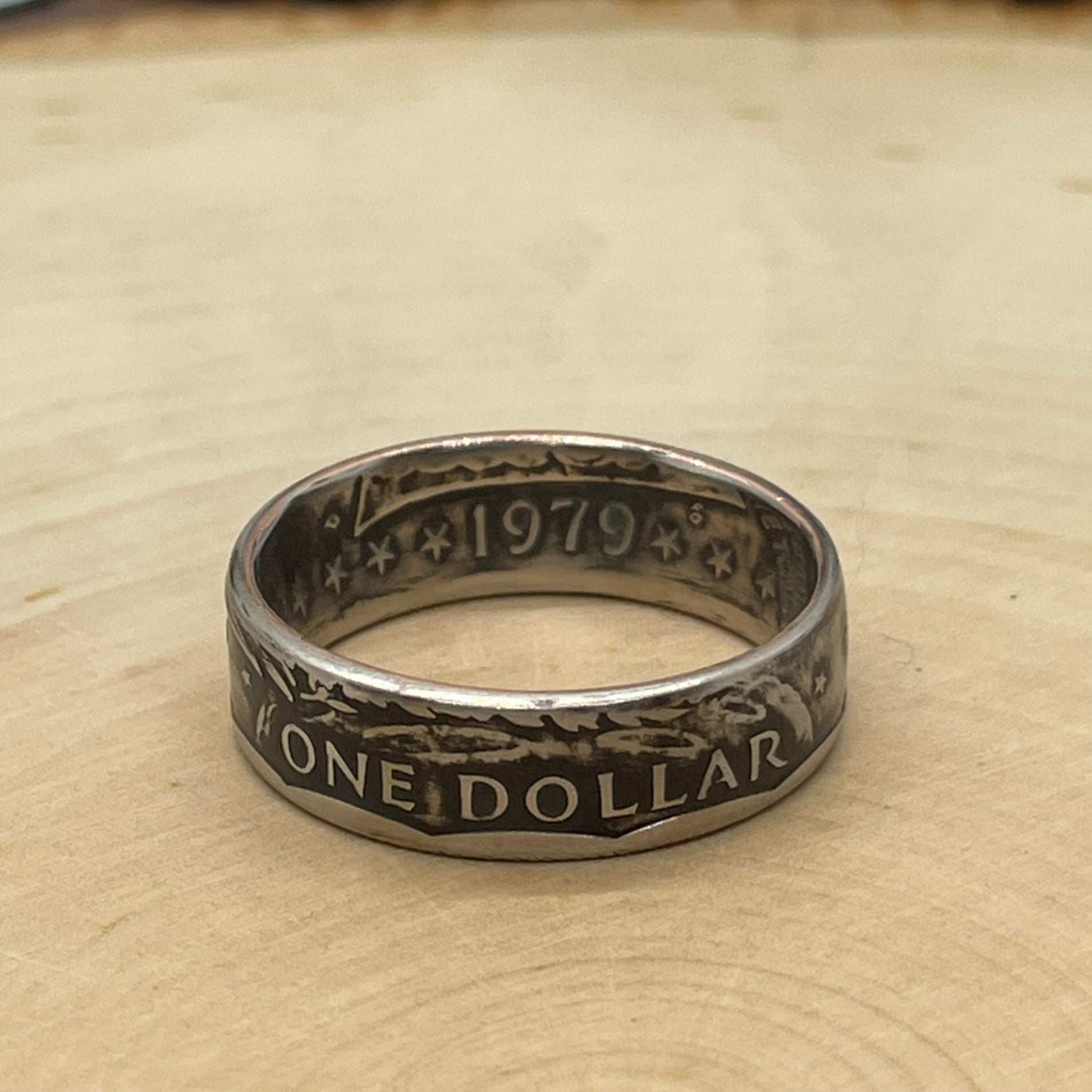 Susan B. Anthony Dollar Coin Ring on a light wood round.