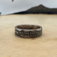 Susan B. Anthony Dollar Coin Ring on a light wood round with mountain outline in background.