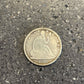 Seated Liberty Silver Half Dollar Coin front on a concrete background.